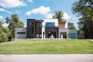 Diseño de fachada de casa actual grande de dos plantas con revestimientos combinados