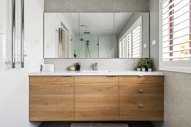 Diseño de cuarto de baño único y a medida actual con armarios con paneles lisos, puertas de armario de madera oscura y baldosas y/o azulejos grises