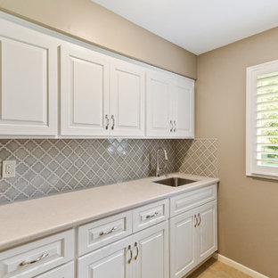 Photo of a medium sized classic single-wall separated utility room in Kansas City with a submerged sink, raised-panel cabinets, white cabinets, engineered stone countertops, beige walls, beige floors and turquoise worktops.