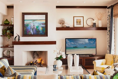 Inspiration for a large eclectic open concept living room in Orange County with white walls, travertine floors, a standard fireplace, a plaster fireplace surround and a built-in media wall.