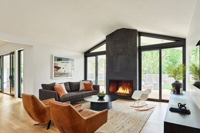 Living room - mid-sized modern open concept light wood floor and vaulted ceiling living room idea in Kansas City with white walls, a wood stove, a brick fireplace and a wall-mounted tv