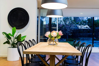 Contemporary dining room in Adelaide with white walls, medium hardwood floors and brown floor.