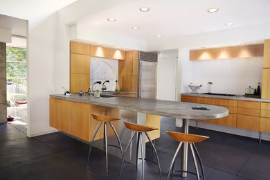 This is an example of a mid-sized modern u-shaped eat-in kitchen in Other with an undermount sink, flat-panel cabinets, medium wood cabinets, concrete benchtops, stainless steel appliances, concrete floors, with island and black floor.