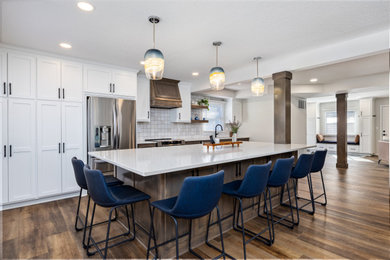 Example of a mid-sized transitional galley laminate floor and brown floor eat-in kitchen design in Minneapolis with an undermount sink, shaker cabinets, medium tone wood cabinets, quartz countertops, white backsplash, ceramic backsplash, stainless steel appliances, an island and beige countertops