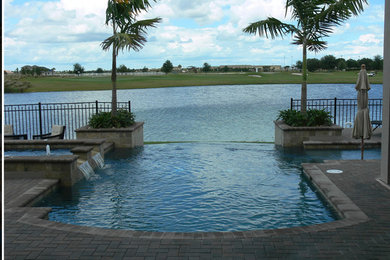 Diseño de piscina con fuente elevada clásica grande a medida en patio trasero con suelo de baldosas