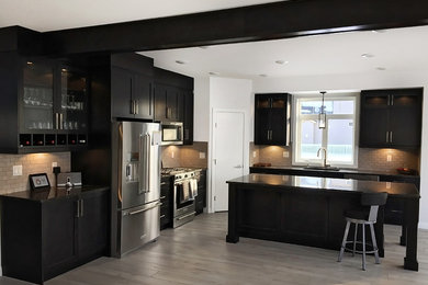 Open concept kitchen - large modern l-shaped light wood floor open concept kitchen idea in Calgary with a double-bowl sink, shaker cabinets, gray cabinets, wood countertops, beige backsplash, ceramic backsplash, stainless steel appliances and an island