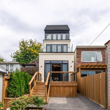 Raised rear deck with black railings above a paved patio and cedar fence, Toront