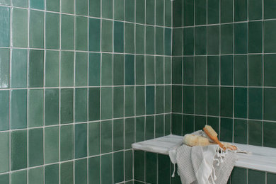 バーミングハムにある中くらいなおしゃれな浴室 (フラットパネル扉のキャビネット、淡色木目調キャビネット、置き型浴槽、アルコーブ型シャワー、緑のタイル、セラミックタイル、白い壁、大理石の床、アンダーカウンター洗面器、人工大理石カウンター、マルチカラーの床、開き戸のシャワー、白い洗面カウンター、シャワーベンチ、洗面台2つ、独立型洗面台) の写真