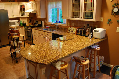 Example of a mid-sized classic u-shaped ceramic tile and brown floor eat-in kitchen design in Boston with an undermount sink, raised-panel cabinets, light wood cabinets, granite countertops, orange backsplash, terra-cotta backsplash, black appliances and an island