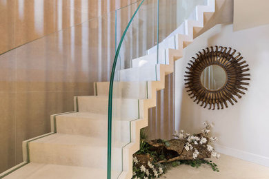Diseño de escalera suspendida actual con escalones de piedra caliza, contrahuellas de piedra caliza y barandilla de vidrio