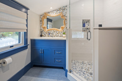 Стильный дизайн: ванная комната среднего размера в морском стиле с фасадами в стиле шейкер, синими фасадами, угловым душем, унитазом-моноблоком, разноцветной плиткой, плиткой из листового стекла, серыми стенами, полом из керамической плитки, душевой кабиной, врезной раковиной, столешницей из искусственного кварца, синим полом, душем с распашными дверями, тумбой под одну раковину и встроенной тумбой - последний тренд