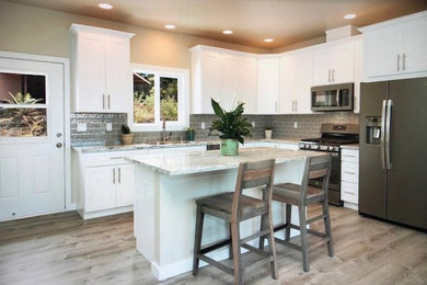 Inspiration for a mid-sized transitional l-shaped separate kitchen in Hawaii with an undermount sink, shaker cabinets, white cabinets, granite benchtops, subway tile splashback, stainless steel appliances, medium hardwood floors, with island and multi-coloured benchtop.