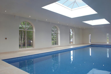 Design ideas for a medium sized modern indoor rectangular swimming pool in Other with a pool house and natural stone paving.