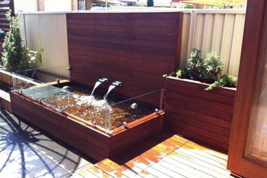 Photo of a contemporary backyard garden in Sydney with a water feature and decking.