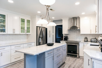 Example of a mid-sized transitional l-shaped vinyl floor and gray floor kitchen design in Philadelphia with a single-bowl sink, shaker cabinets, white cabinets, quartz countertops, white backsplash, porcelain backsplash, an island and multicolored countertops
