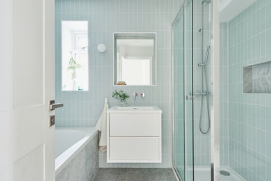 Bild på ett mellanstort funkis vit vitt badrum för barn, med släta luckor, vita skåp, ett platsbyggt badkar, en kantlös dusch, en vägghängd toalettstol, grön kakel, porslinskakel, vita väggar, klinkergolv i keramik, ett nedsänkt handfat, bänkskiva i akrylsten, flerfärgat golv och dusch med skjutdörr