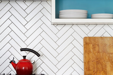 1950s medium tone wood floor eat-in kitchen photo in Toronto with a double-bowl sink, flat-panel cabinets, white cabinets, quartz countertops, white backsplash, ceramic backsplash, stainless steel appliances and an island