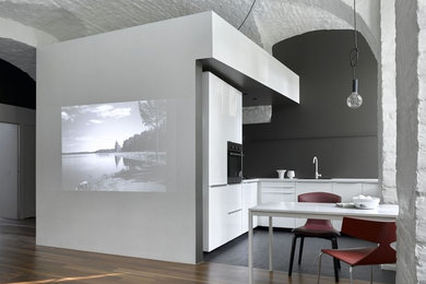 Inspiration for a contemporary l-shaped open plan kitchen in Moscow with a drop-in sink, flat-panel cabinets, black splashback, stainless steel appliances, slate floors, no island, black floor and white benchtop.