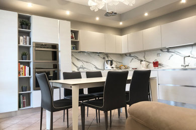 Photo of a large modern l-shaped open plan kitchen in Other with a double-bowl sink, flat-panel cabinets, white cabinets, quartzite benchtops, white splashback, stainless steel appliances, slate floors, no island, beige floor and multi-coloured benchtop.