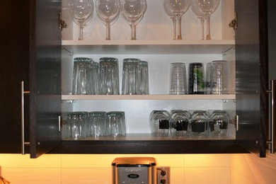 Example of a large minimalist single-wall dark wood floor open concept kitchen design in Seattle with a drop-in sink, flat-panel cabinets, dark wood cabinets, granite countertops, white backsplash, ceramic backsplash, stainless steel appliances and an island