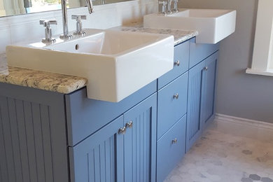 Photo of a transitional master bathroom in Denver with beaded inset cabinets, blue cabinets, a drop-in tub, a double shower, a two-piece toilet, blue tile, subway tile, grey walls, marble floors and granite benchtops.