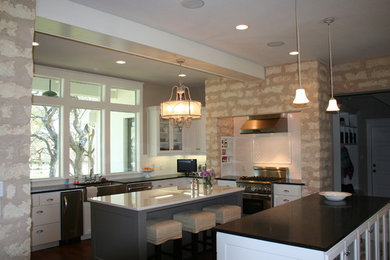 Country u-shaped medium tone wood floor eat-in kitchen photo in Austin with a farmhouse sink, flat-panel cabinets, white cabinets, granite countertops, white backsplash, subway tile backsplash, stainless steel appliances and two islands