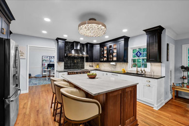 Eat-in kitchen - large transitional u-shaped light wood floor and yellow floor eat-in kitchen idea in Louisville with an undermount sink, shaker cabinets, black cabinets, soapstone countertops, white backsplash, ceramic backsplash, stainless steel appliances, an island and black countertops