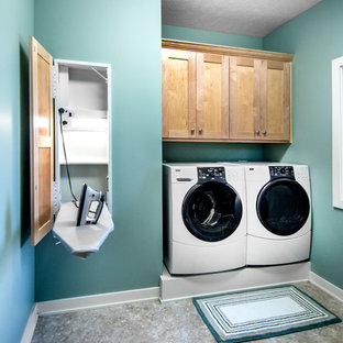 Diseño de cuarto de lavado lineal, de estilo americano, pequeño, con armarios estilo shaker, paredes azules, suelo de linóleo, lavadora y secadora juntas y puertas de armario de madera oscura