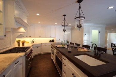 This is an example of a large traditional l-shaped eat-in kitchen in New York with a farmhouse sink, recessed-panel cabinets, white cabinets, marble benchtops, white splashback, ceramic splashback, stainless steel appliances and with island.