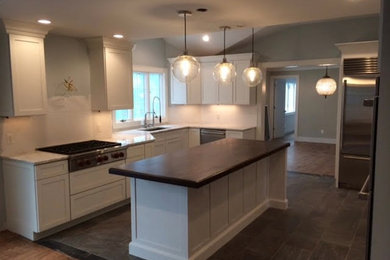 Photo of a mid-sized modern u-shaped open plan kitchen in New York with an undermount sink, shaker cabinets, white cabinets, marble benchtops, white splashback, stone slab splashback, stainless steel appliances, ceramic floors, with island and grey floor.