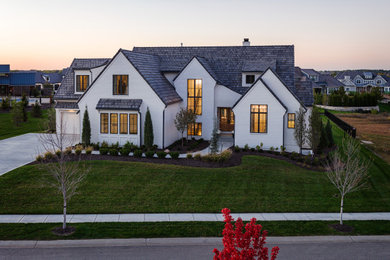 Inspiration for a large french country white three-story house exterior remodel in Kansas City with a gray roof