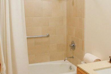 Example of an asian beige tile and stone tile tub/shower combo design in Portland with an undermount sink, flat-panel cabinets, medium tone wood cabinets, quartzite countertops and a one-piece toilet