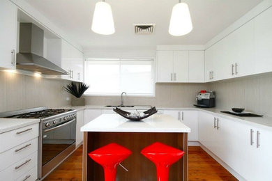 Photo of a mid-sized modern u-shaped separate kitchen in Sydney with a double-bowl sink, limestone benchtops, beige splashback, ceramic splashback, stainless steel appliances, light hardwood floors and with island.