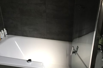 Exemple d'une salle de bain moderne avec une baignoire posée, un combiné douche/baignoire, un carrelage gris, des carreaux de céramique, un mur gris et un sol en carrelage de porcelaine.