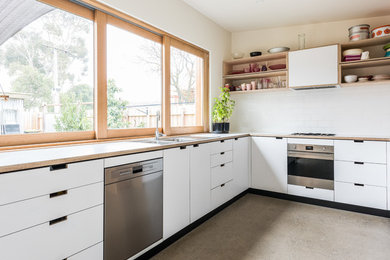 Contemporary galley eat-in kitchen in Melbourne with a double-bowl sink, flat-panel cabinets, white cabinets, wood benchtops, stainless steel appliances, concrete floors, no island and white benchtop.
