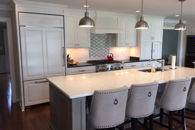 Large elegant medium tone wood floor and brown floor eat-in kitchen photo in Other with a single-bowl sink, raised-panel cabinets, white cabinets, quartz countertops, multicolored backsplash, mosaic tile backsplash, paneled appliances and two islands