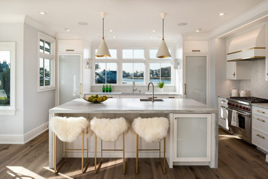 Design ideas for a large beach style l-shaped eat-in kitchen in New York with an undermount sink, recessed-panel cabinets, white cabinets, marble benchtops, multi-coloured splashback, mosaic tile splashback, panelled appliances, light hardwood floors, with island and grey benchtop.