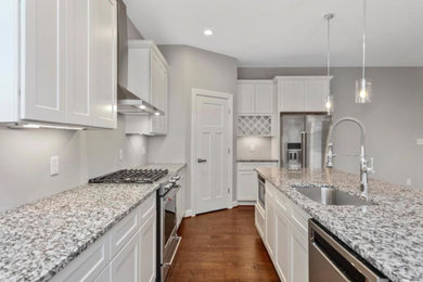 Inspiration for a mid-sized modern l-shaped medium tone wood floor eat-in kitchen remodel in Other with a single-bowl sink, shaker cabinets, white cabinets, granite countertops, stainless steel appliances, an island and multicolored countertops