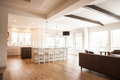 Photo of a large traditional l-shaped open plan kitchen in Vancouver with a submerged sink, shaker cabinets, white cabinets, engineered stone countertops, white splashback, stainless steel appliances, medium hardwood flooring, multiple islands, brown floors, white worktops and a coffered ceiling.