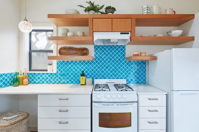 Small trendy single-wall brown floor enclosed kitchen photo in Austin with flat-panel cabinets, white cabinets, blue backsplash, white appliances, no island and white countertops