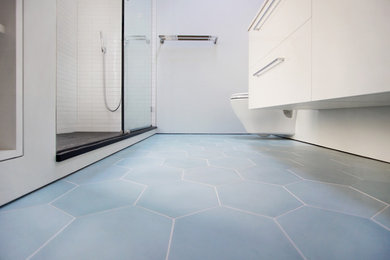 Mid-sized minimalist 3/4 white tile and subway tile cement tile floor and blue floor bathroom photo in Other with white cabinets, a wall-mount toilet, white walls, an integrated sink and solid surface countertops