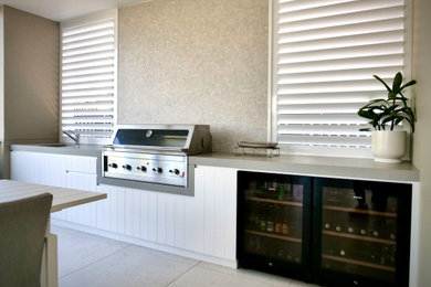 Inspiration for a contemporary backyard and ground level deck in Sydney with an outdoor kitchen and a roof extension.