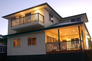 Photo of a mid-sized modern two-storey house exterior in Brisbane with vinyl siding, a hip roof and a metal roof.