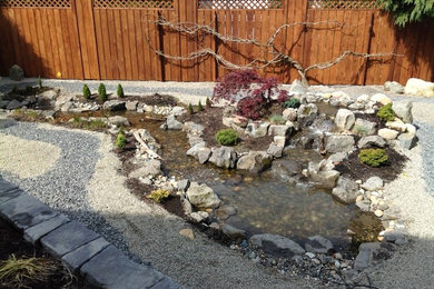 Inspiration for a mid-sized asian backyard partial sun formal garden for spring in Vancouver with a water feature and gravel.