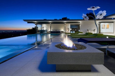 Huge minimalist backyard concrete patio photo in Los Angeles with a fire pit and a roof extension