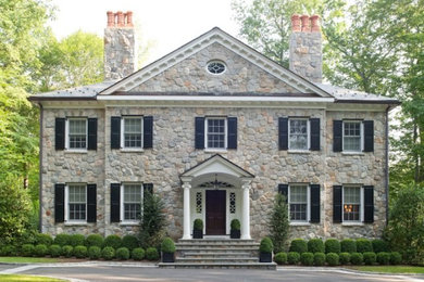 Photo of a large traditional three-storey house exterior in New York with stone veneer, a gable roof and a tile roof.