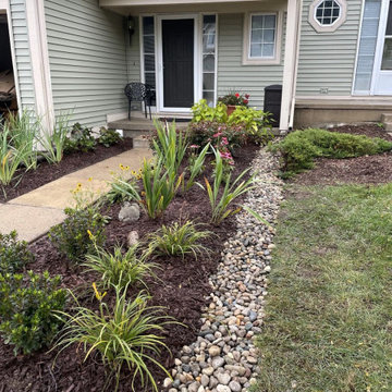 Front bed with a river rock drain channel carrying downspout water away from the