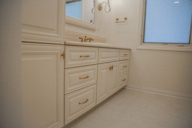 Example of a mid-sized classic beige tile and ceramic tile porcelain tile, beige floor and single-sink bathroom design in Other with raised-panel cabinets, beige cabinets, white walls, a drop-in sink, quartz countertops, beige countertops and a built-in vanity