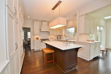 Eat-in kitchen - mid-sized traditional u-shaped medium tone wood floor eat-in kitchen idea in DC Metro with a drop-in sink, raised-panel cabinets, white cabinets, solid surface countertops, white backsplash, subway tile backsplash, stainless steel appliances and an island