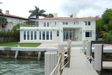 Photo of a large beach style two-storey stucco white house exterior in Miami with a hip roof and a shingle roof.